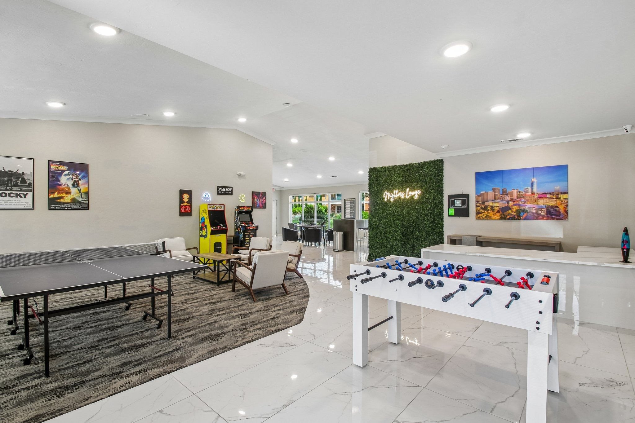 A foosball table is in the middle of a room with a ping pong table and a pool table.